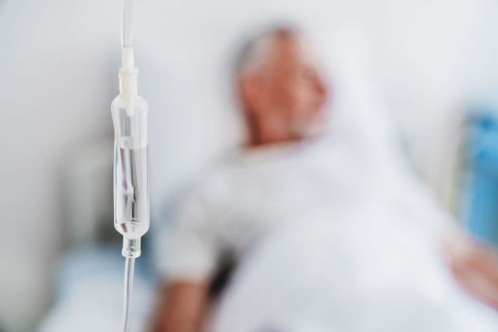 Nahaufnahme von iv Tropfer und Patient im Hintergrund
