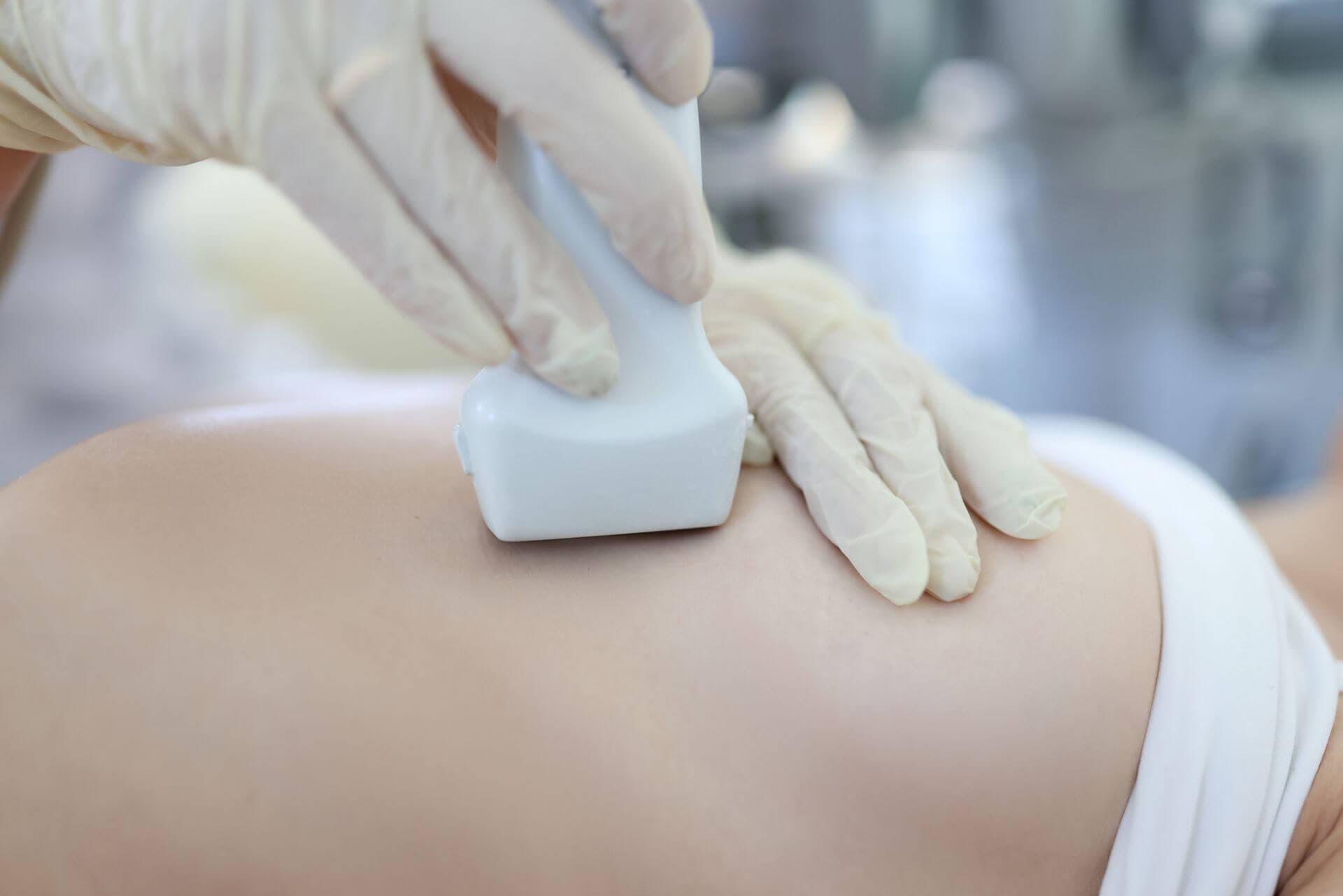 Doctor conducts ultrasound examination of mammary glands of woman. Diagnostics of female breast concept