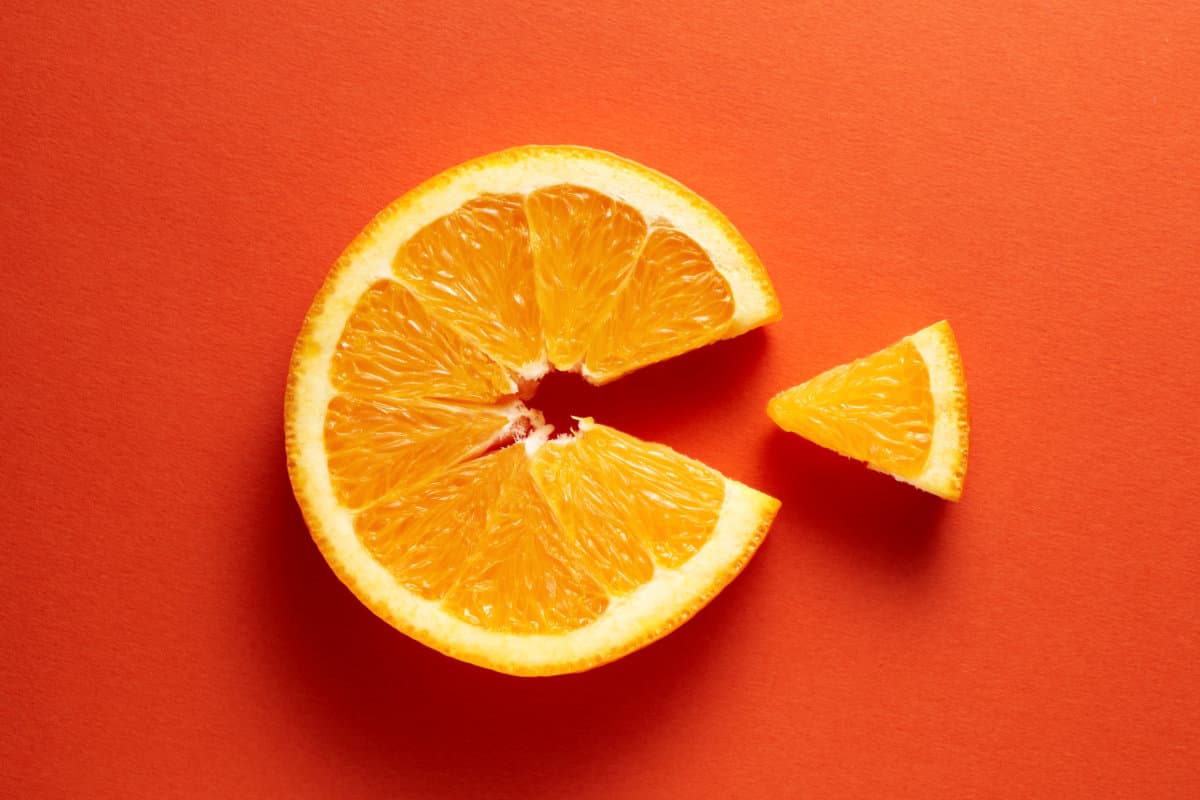 Orange slice symbolizing vitamin c is eating the cut out piece on orange background. Healthy nutrition and immune system.