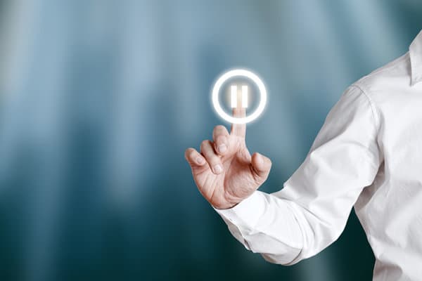 Male hand pressing pause icon on a virtual display screen.