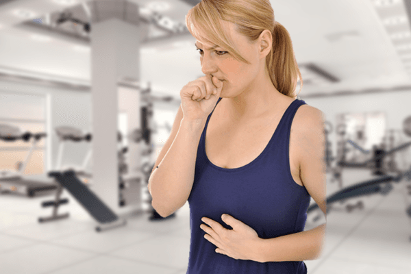 Junge Frau im Fitnesscenter mit Sodbrennen und Aufstossen.