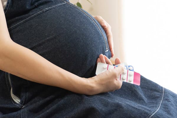 Schwangere Frau mit Medikamenten in der Hand