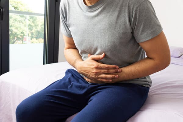 Homme assis sur le lit avec des crampes d'estomac