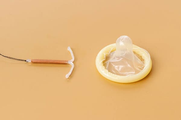 T-förmiges intrauterines Verhütungsmittel mit Kondomen. Konzept der Empfängnisverhütung.