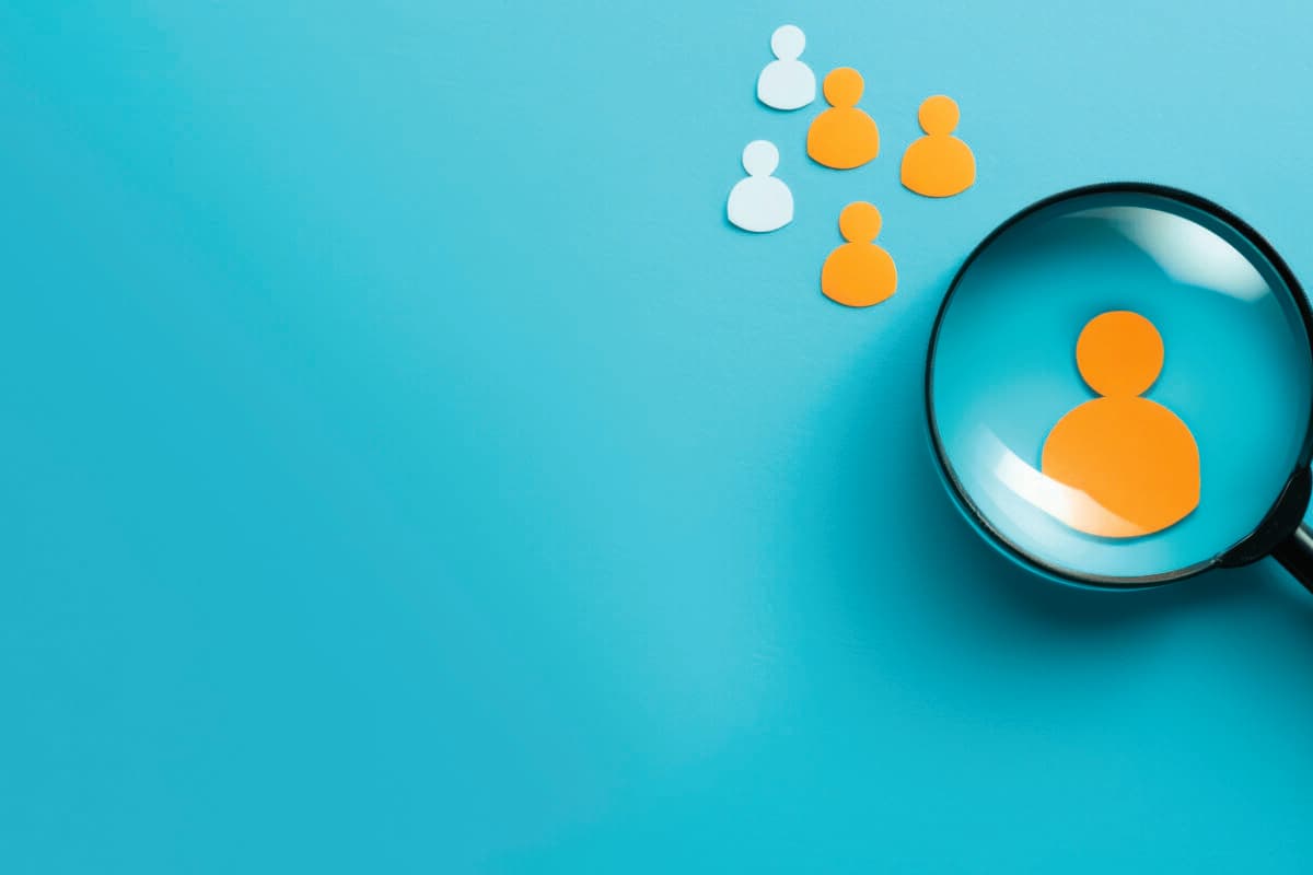 Yellow human icon in magnifying glass among white icons on blue background symbolizing customer focus hr recruitment and crm management banner with space for copy and orange accents