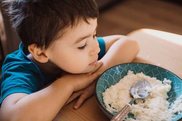 Un garçon assis à table ne veut pas manger.