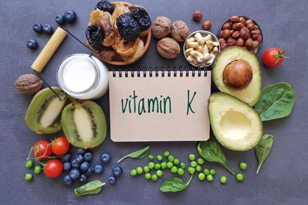 Vitamin K reiche Lebensmittel auf einem Tisch mit einem Zettel in der Mitte auf dem steht "Vitamin K"