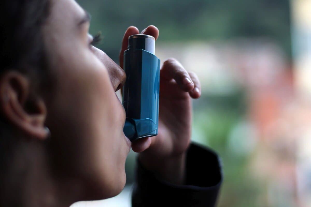 Junge Patientin verwendet einen blauen Asthma-Inhalator zur Vorbeugung eines Asthmaanfalls.