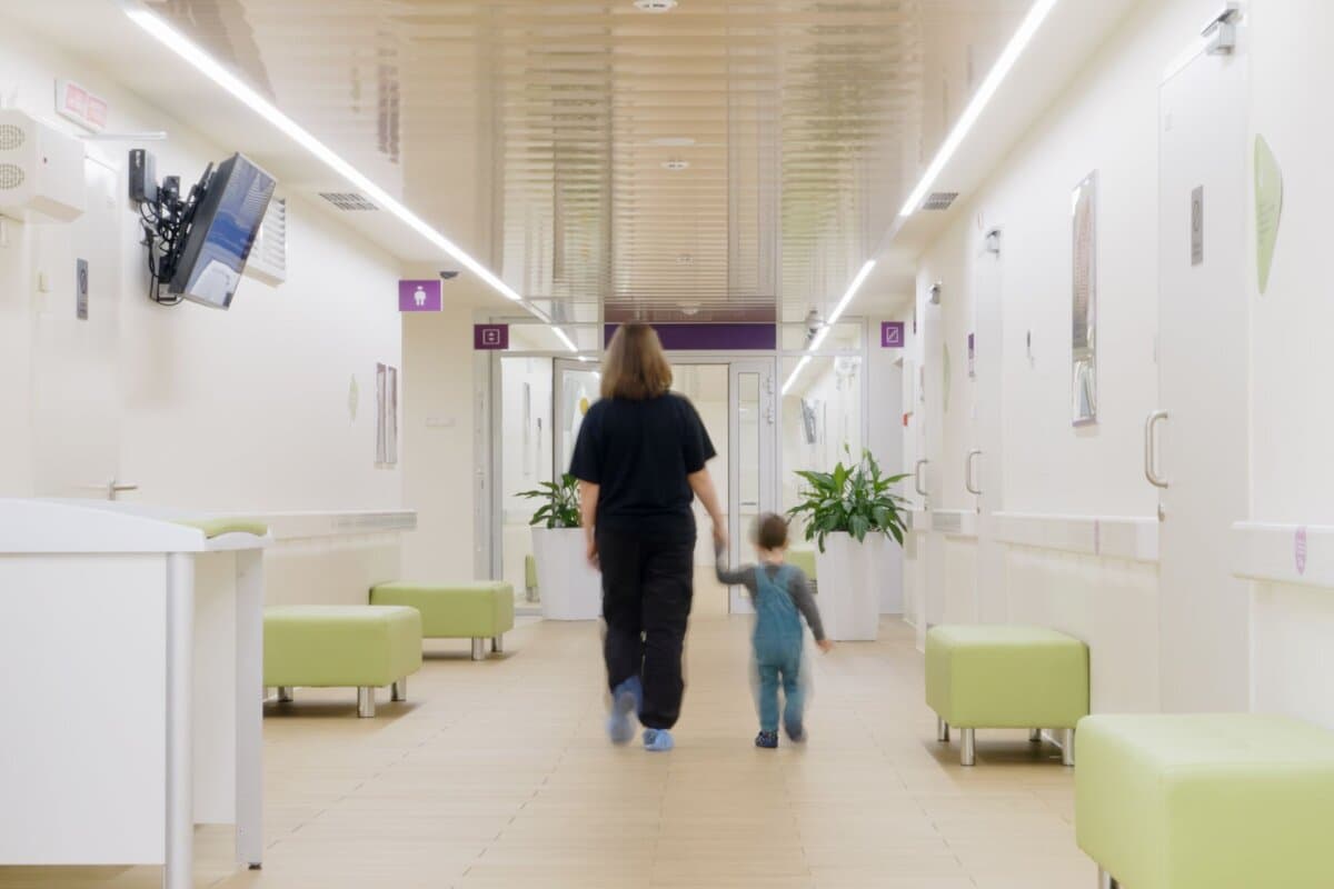 Eine Mutter geht mit ihrem Kind über den Korridor eines Spitals.