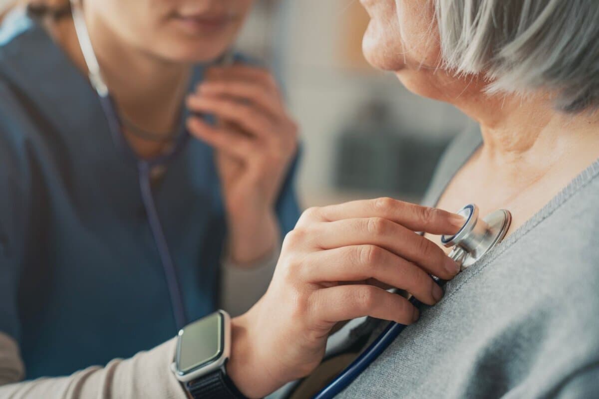 Ärztin hört das Herz einer älteren Patientin ab.