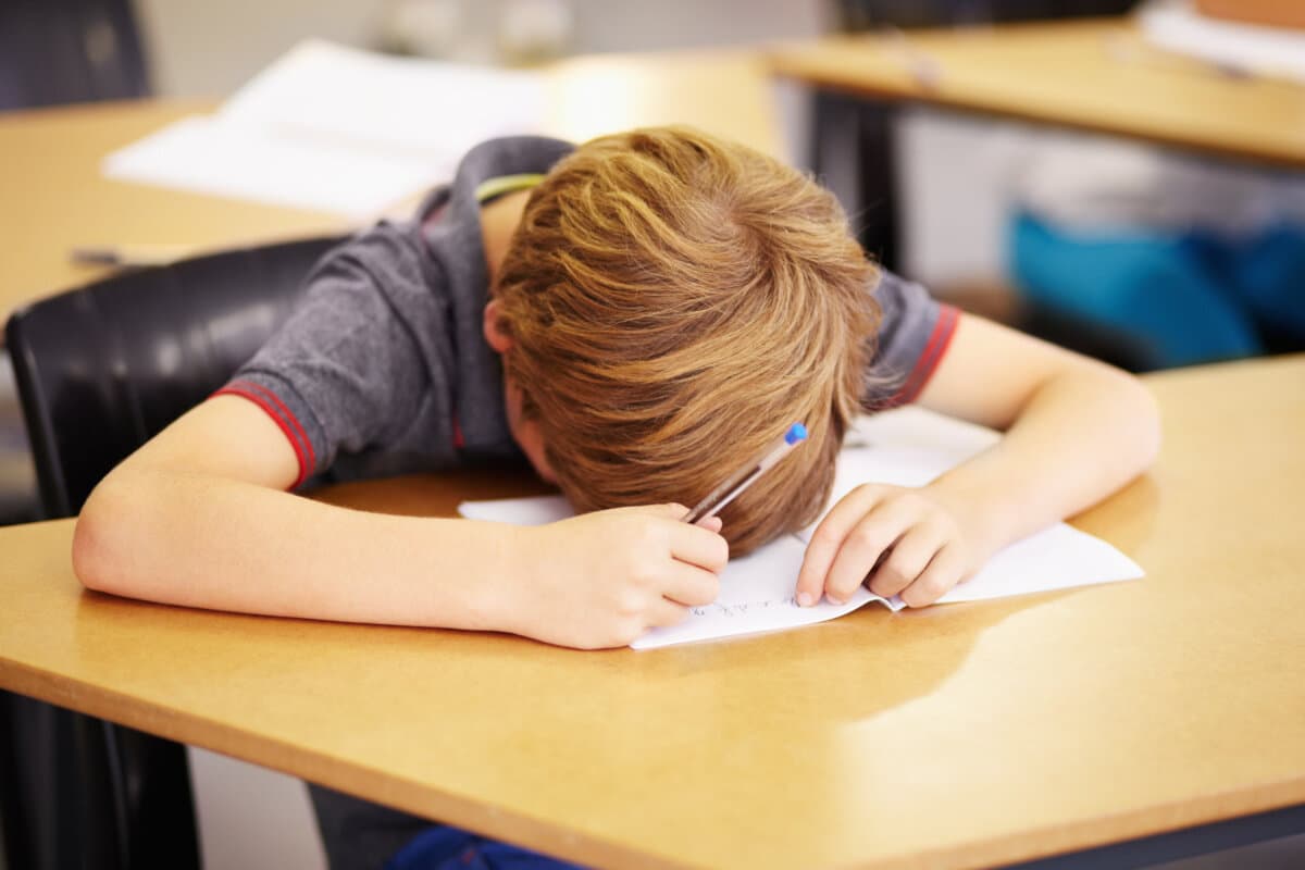 Sleeping, bored and tired with boy in classroom for learning, education and knowledge.