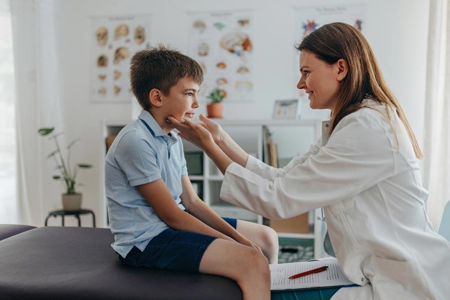 Ärztin untersucht beim Kind die Lymphknoten