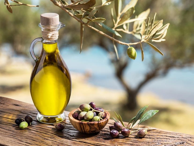 Olivenöl Flasche drumherum ein paar Oliven