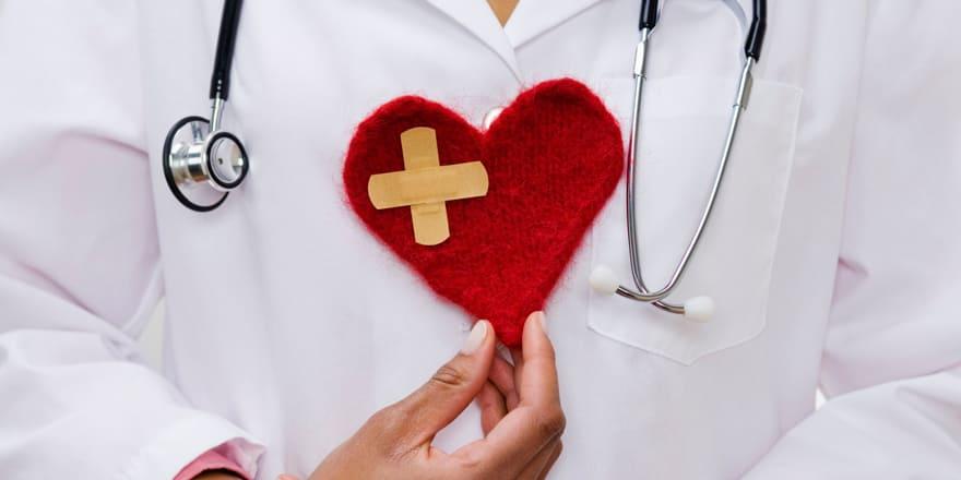 Arzt hält ein rotes Herz aus Filz in der Hand
