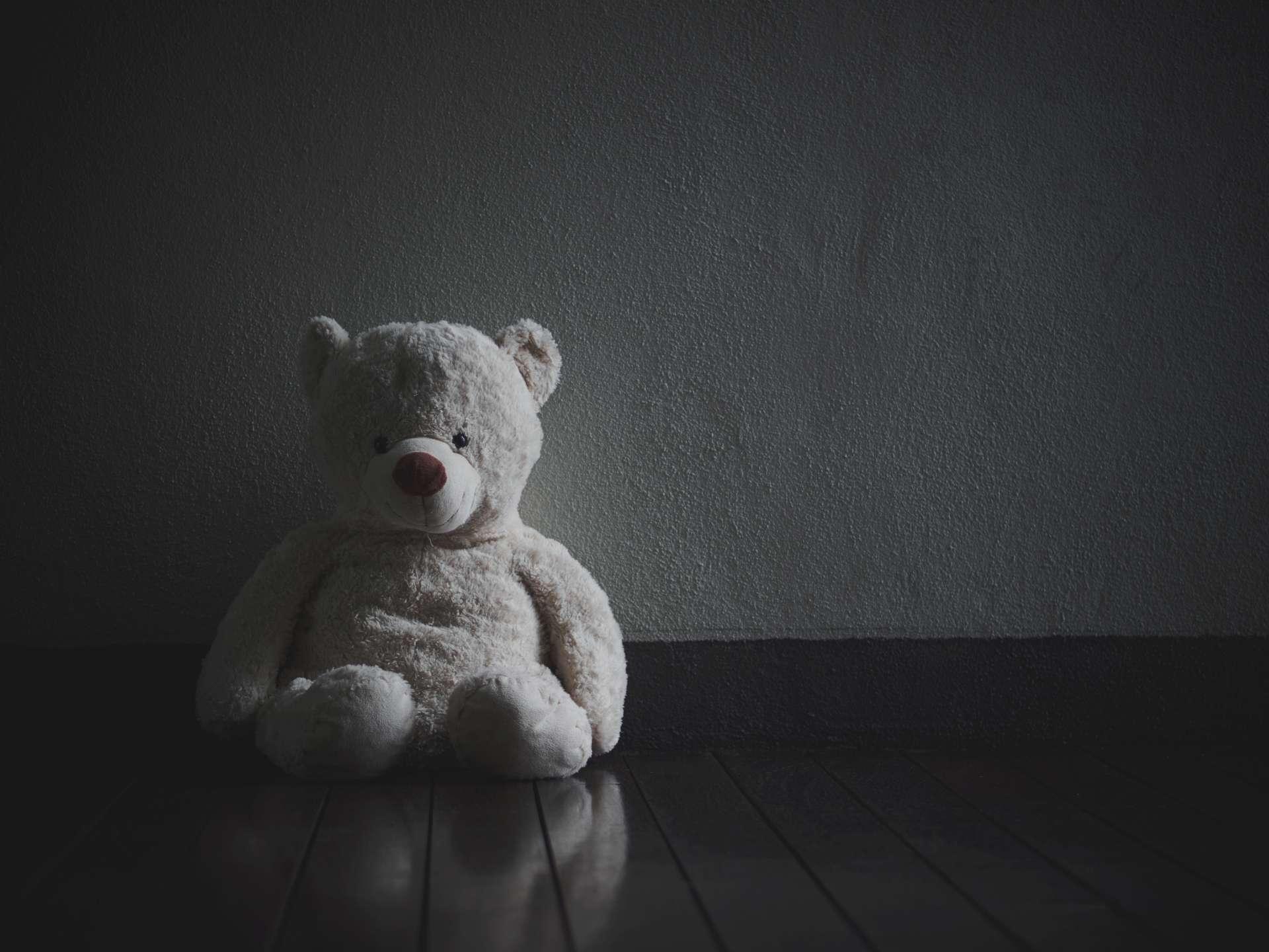 Einsamer Teddybär sitzt im dunklen Raum (Konzept über die Liebe)