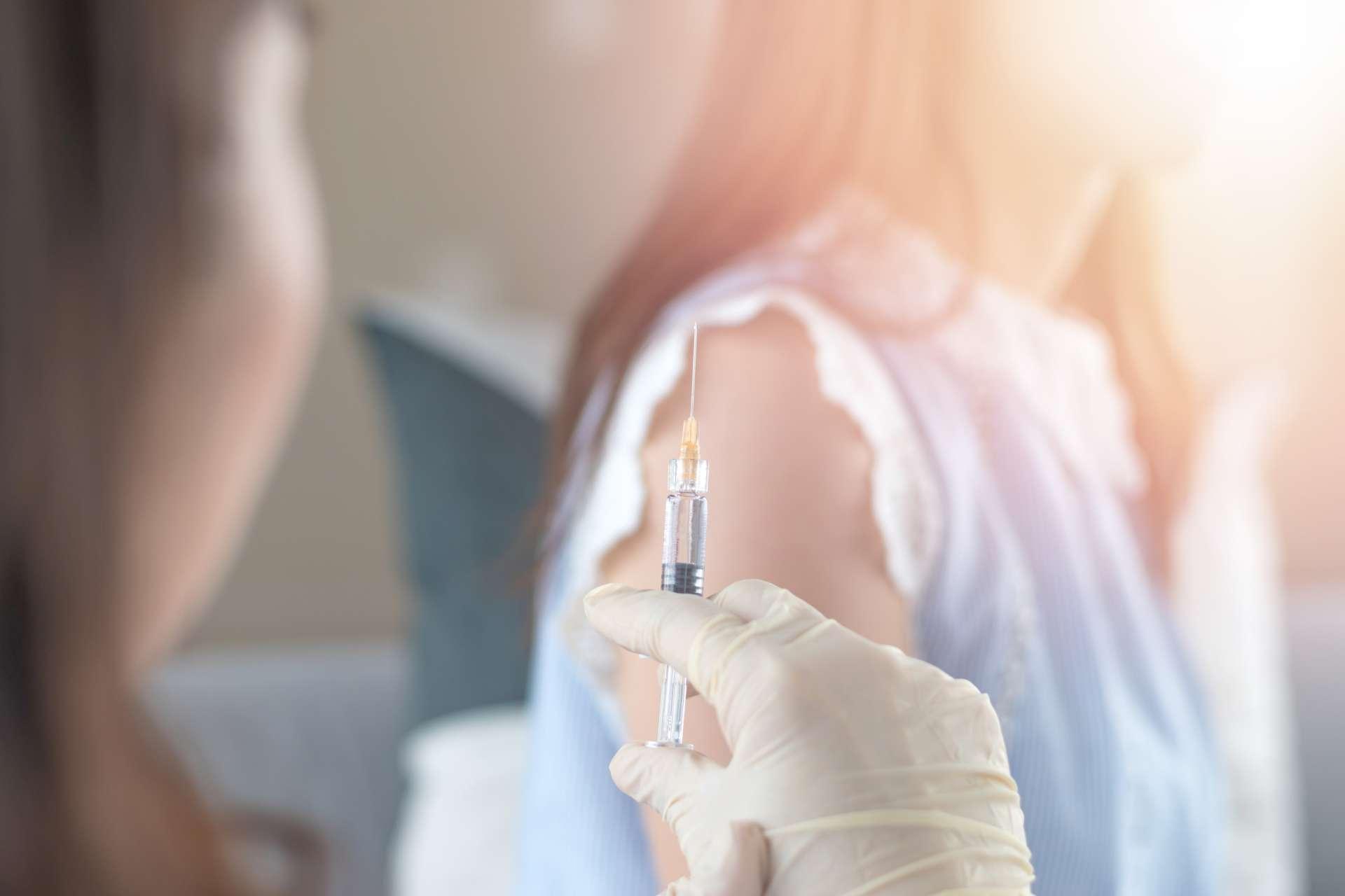 Weltimpfwoche und Konzept des Internationalen HPV-Sensibilisierungstages. Frau mit Impfung gegen Influenza oder Grippeimpfung oder HPV-Prävention mit Spritze durch Krankenschwester oder Arzt.