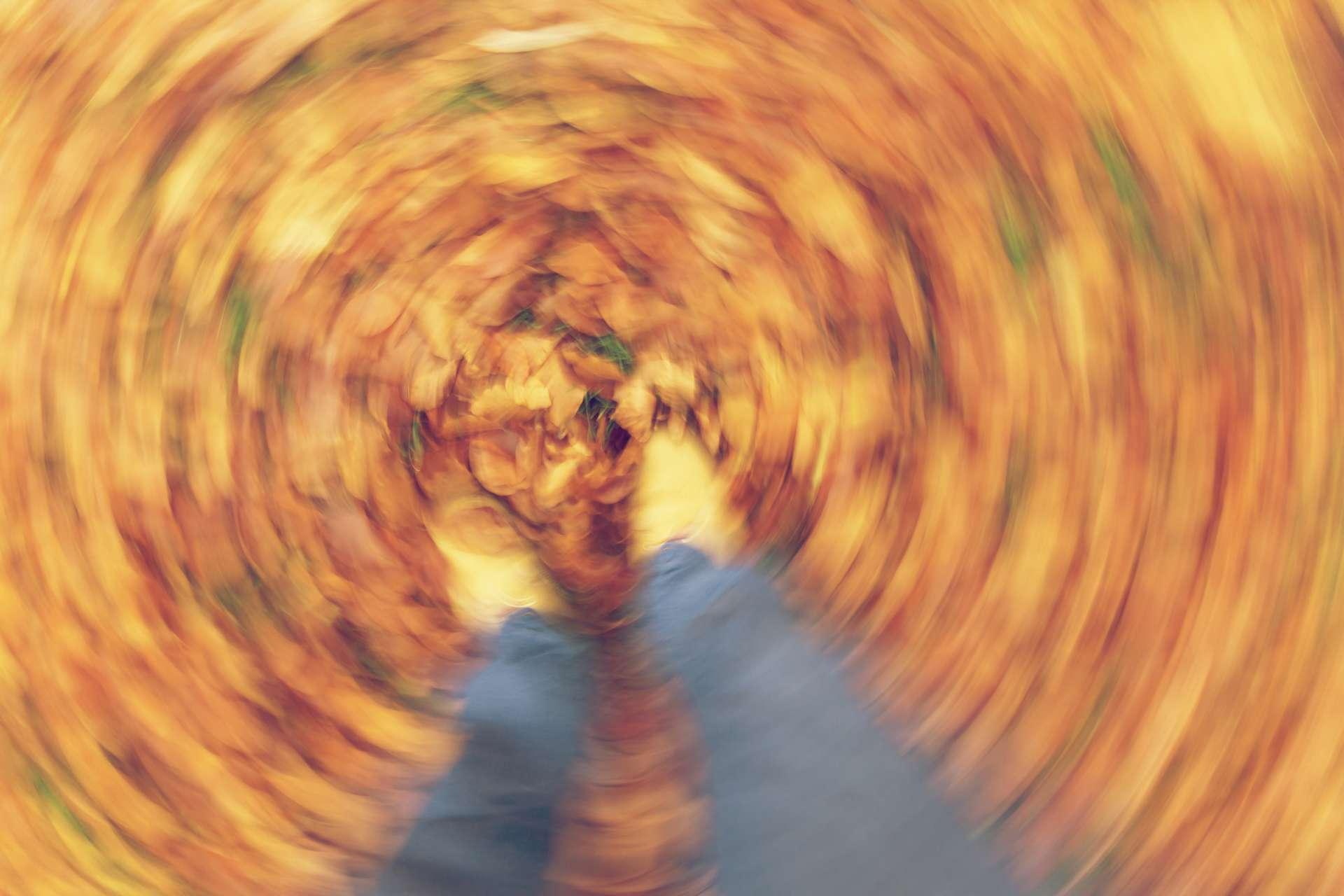 Bewegungsunscharfe Fotografie von Mann- oder Frauenfüßen, die durch goldenes Herbst- oder Herbstlaub gehen