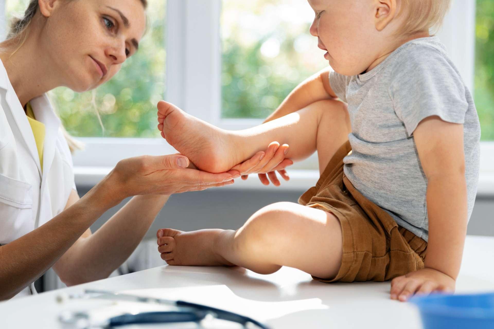 Orthopäde Podologe prüft den Zustand der Füße des Kinderpatienten im Klinikbüro