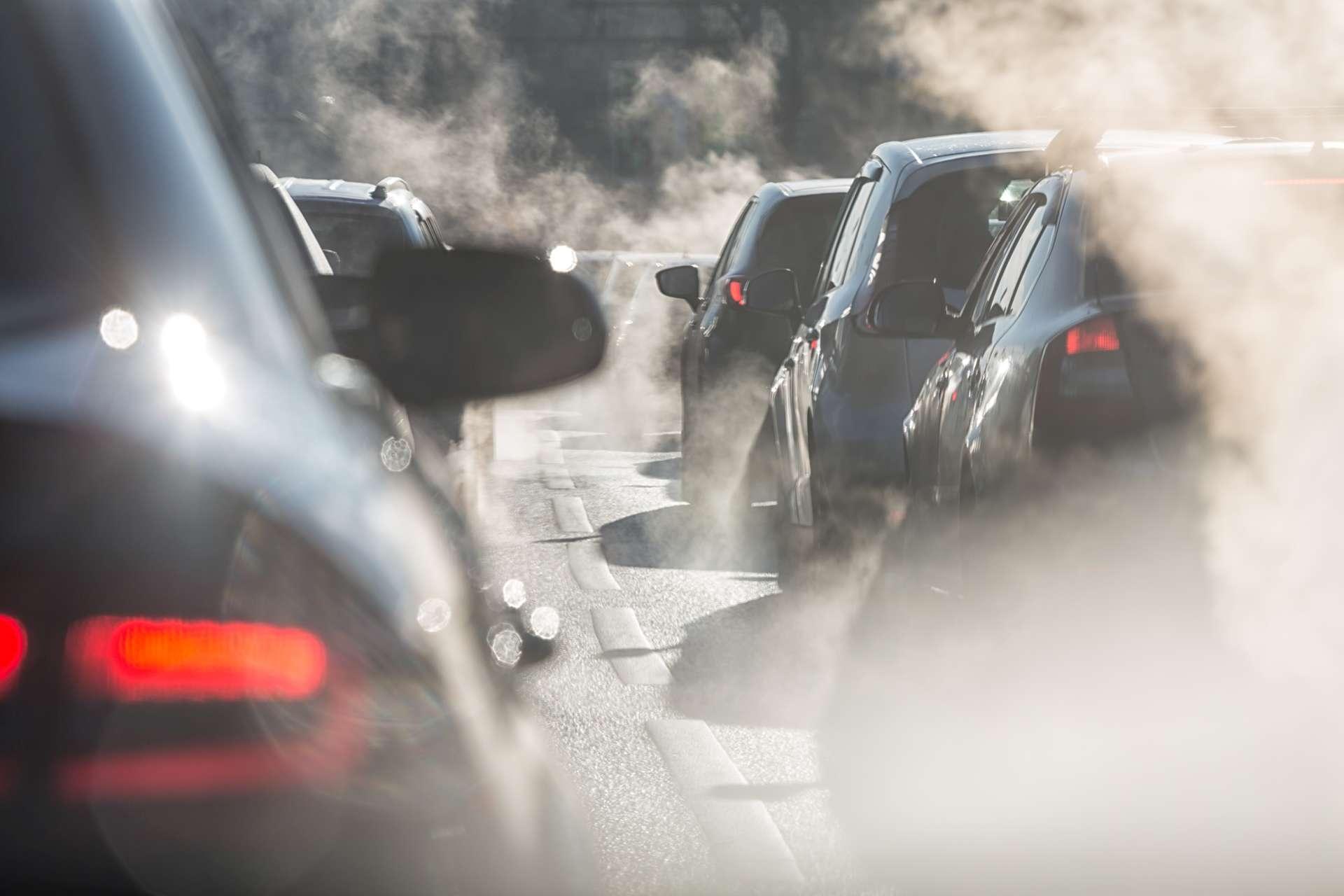 Verschwommene Silhouetten von Autos, umgeben von Dampf aus den Auspuffrohren