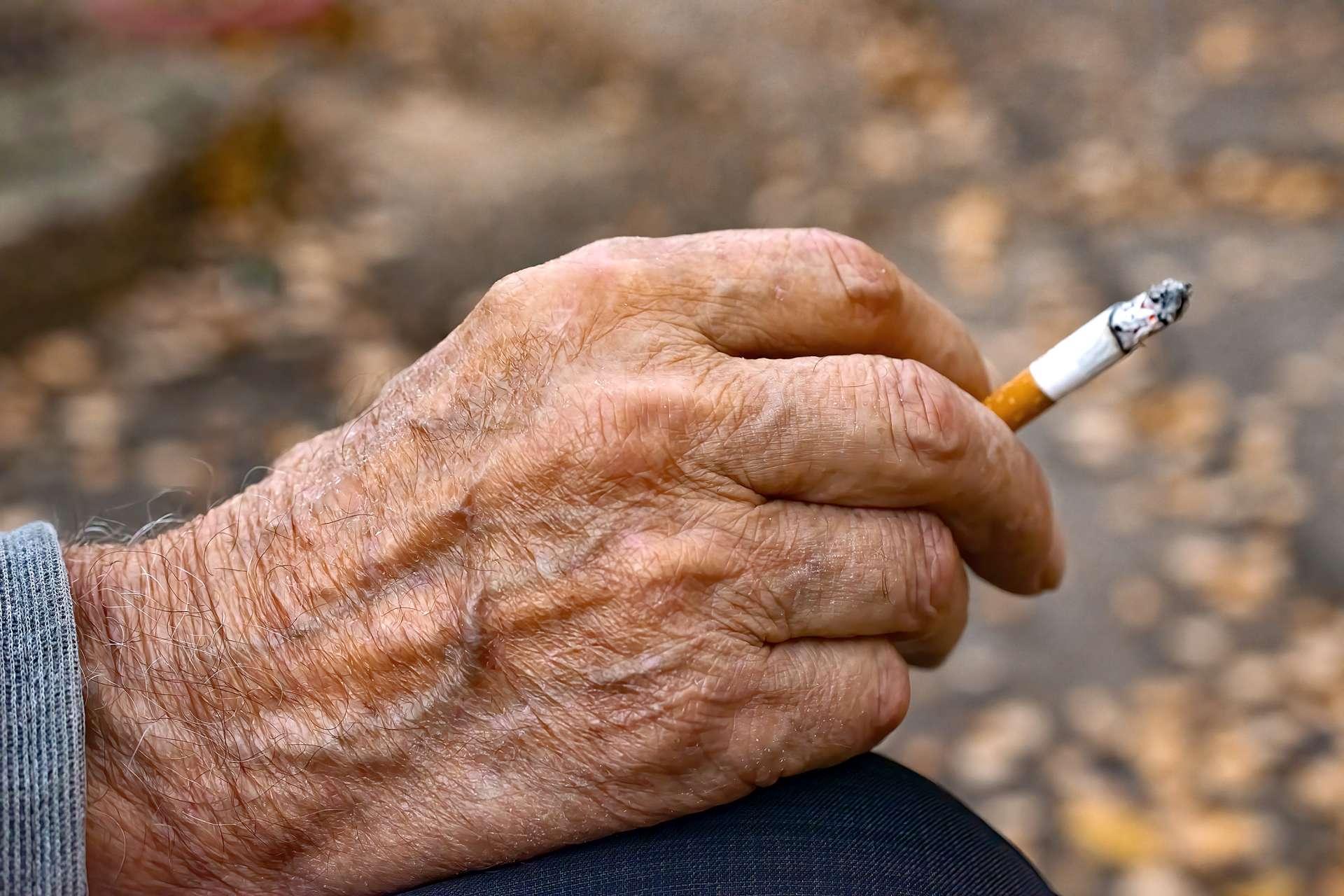 Hand eines sehr alten Mannes mit Zigarette