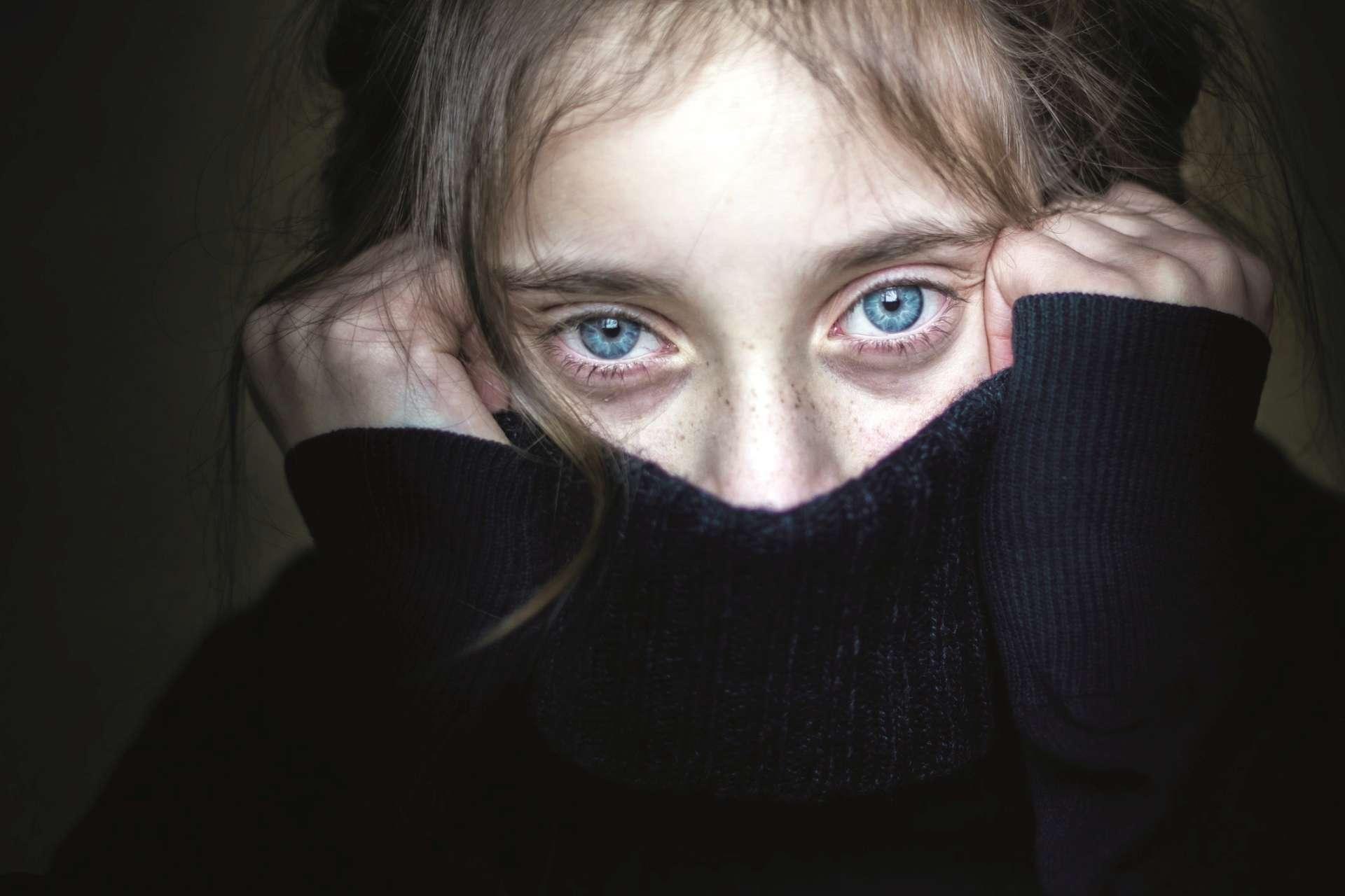 Besorgtes und verängstigtes Mädchen versteckt ihr Gesicht