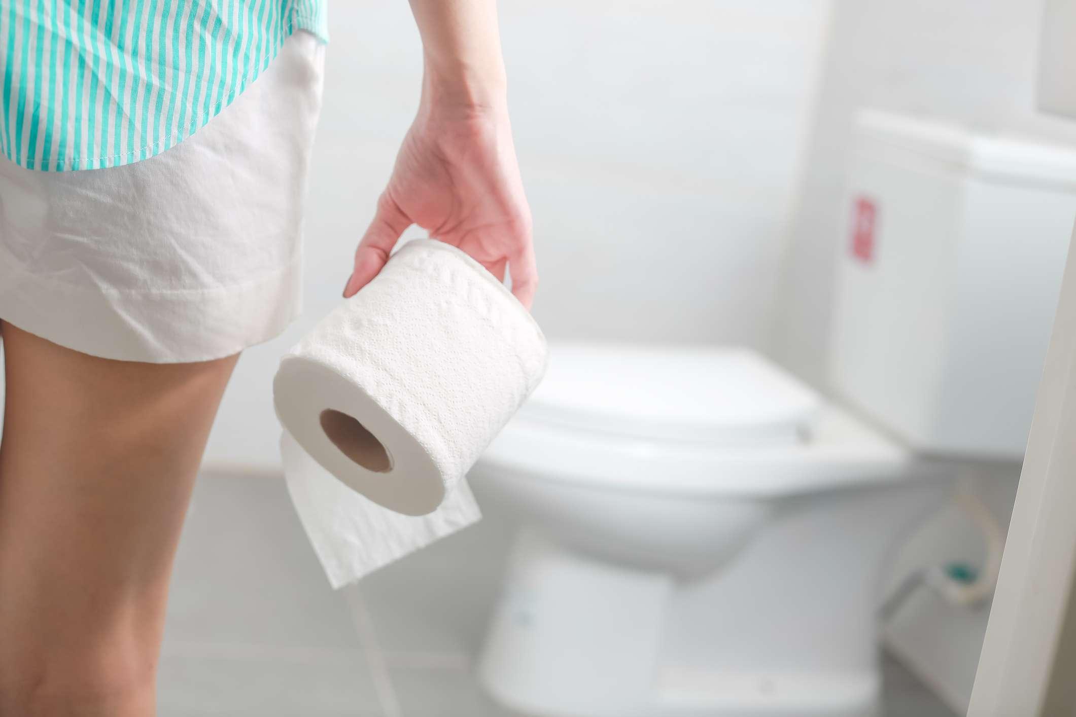 Frau, die Papierrolle hält und an Durchfall in der Toilette leidet.