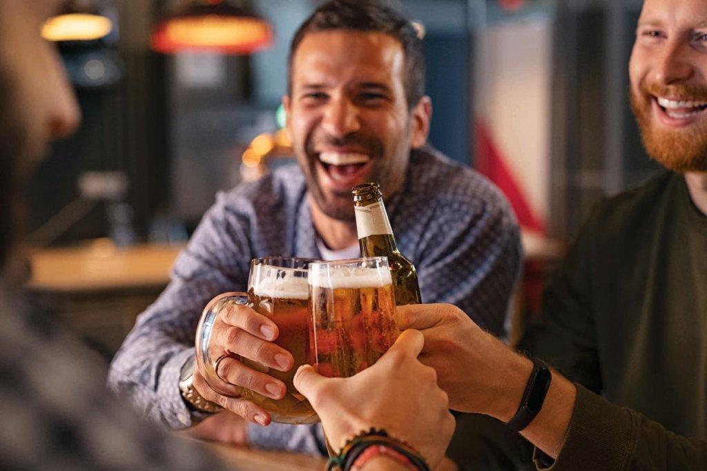 Drei Männer stossen mit Bier an