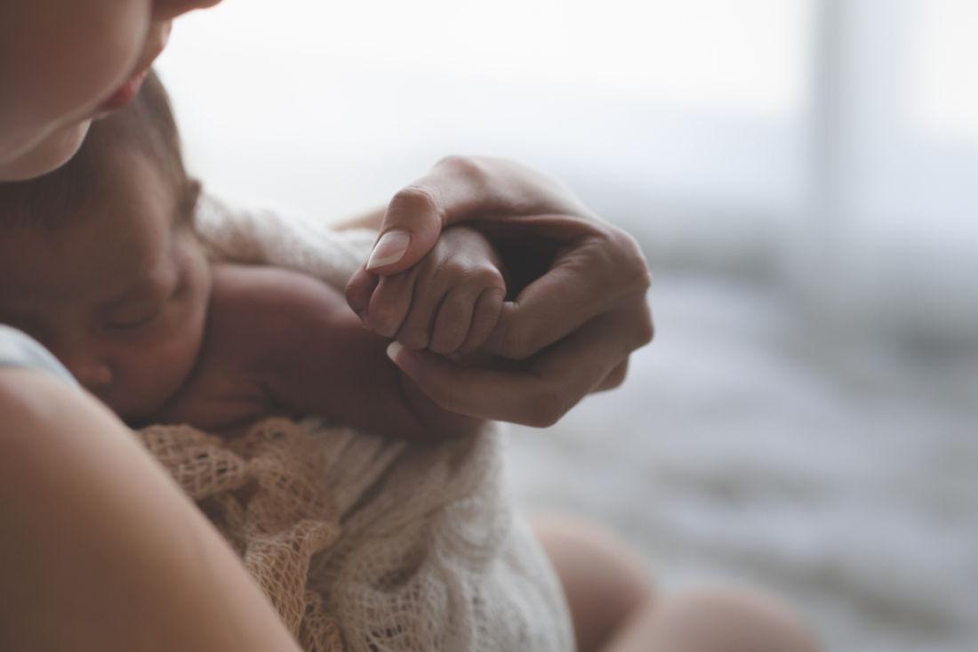 Eine Frau hält die Hand eines Neugeborenen