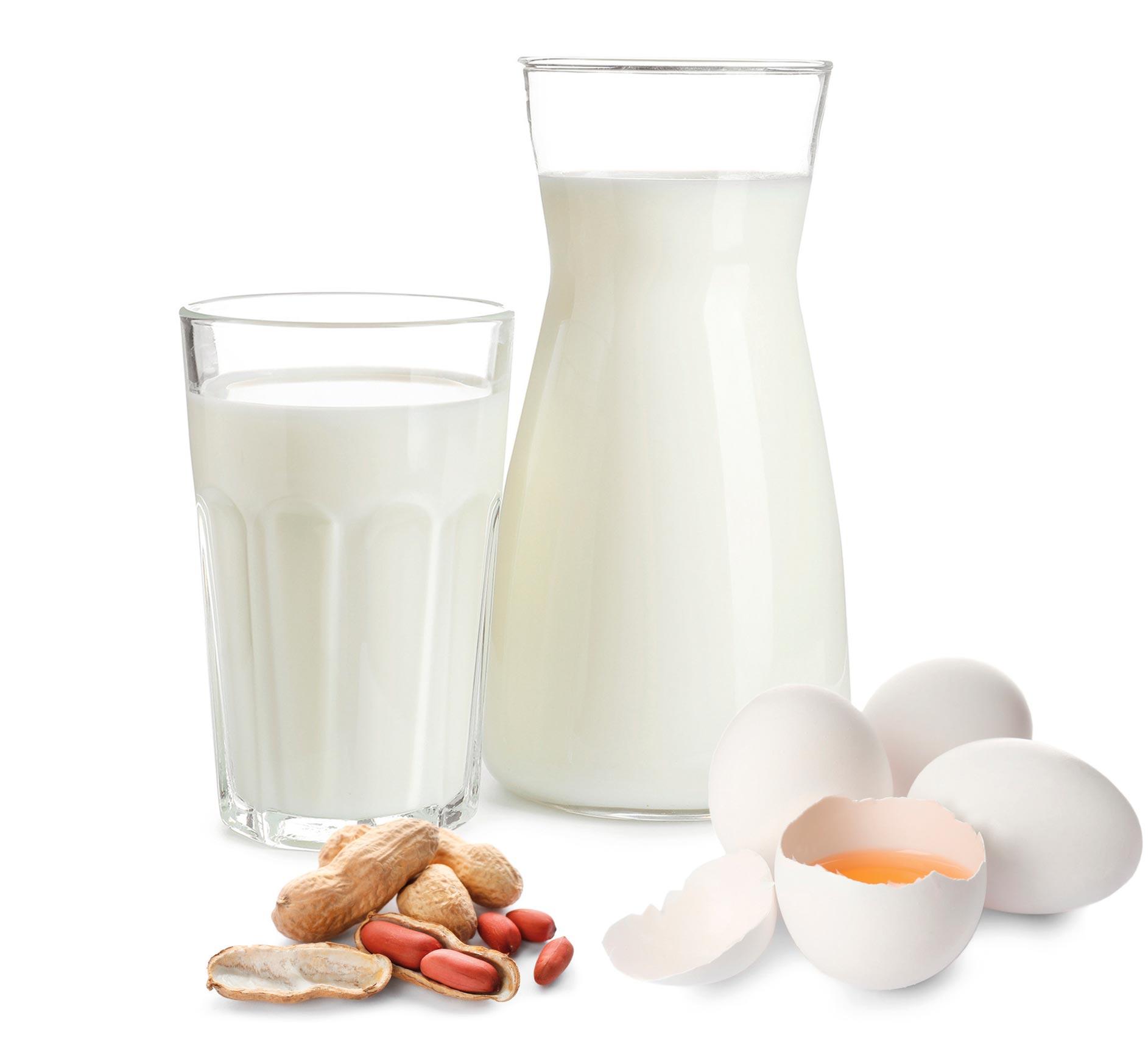 Milch im Krug und Glas sowie Eier und Erdnüsse