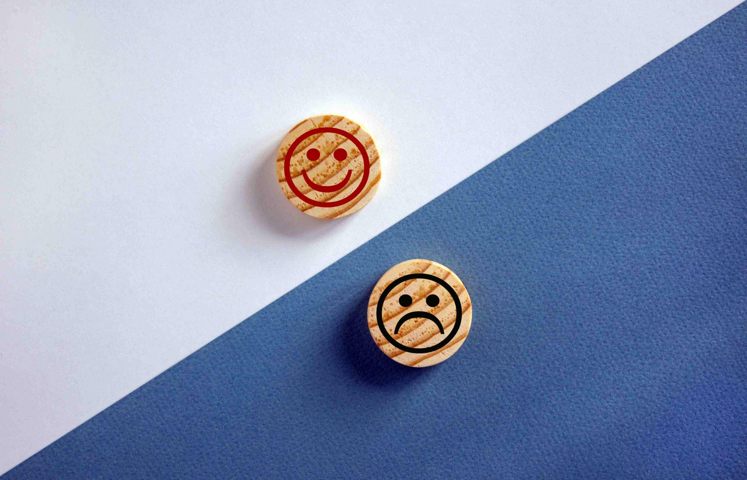Das Konzept der Gegensätze, Holzkreise mit Lächeln auf blauem und weißem Hintergrund, flache Lage, Kopierraum.