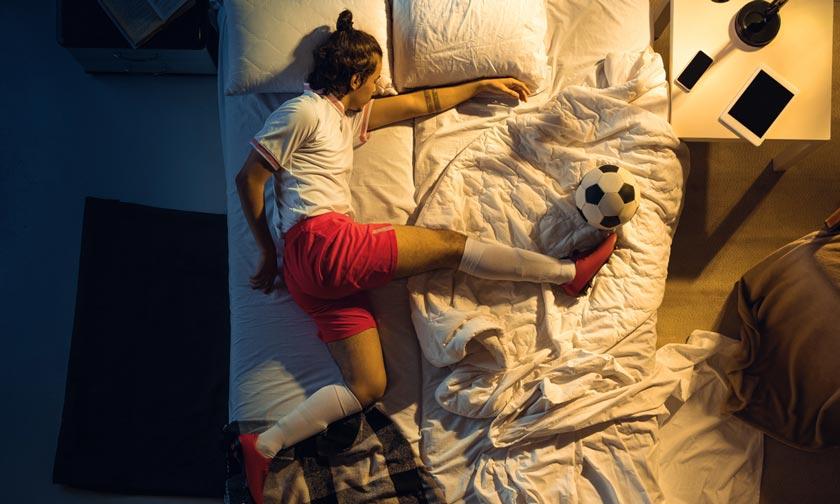 Kind mit Fussball Kleider auf dem Bett