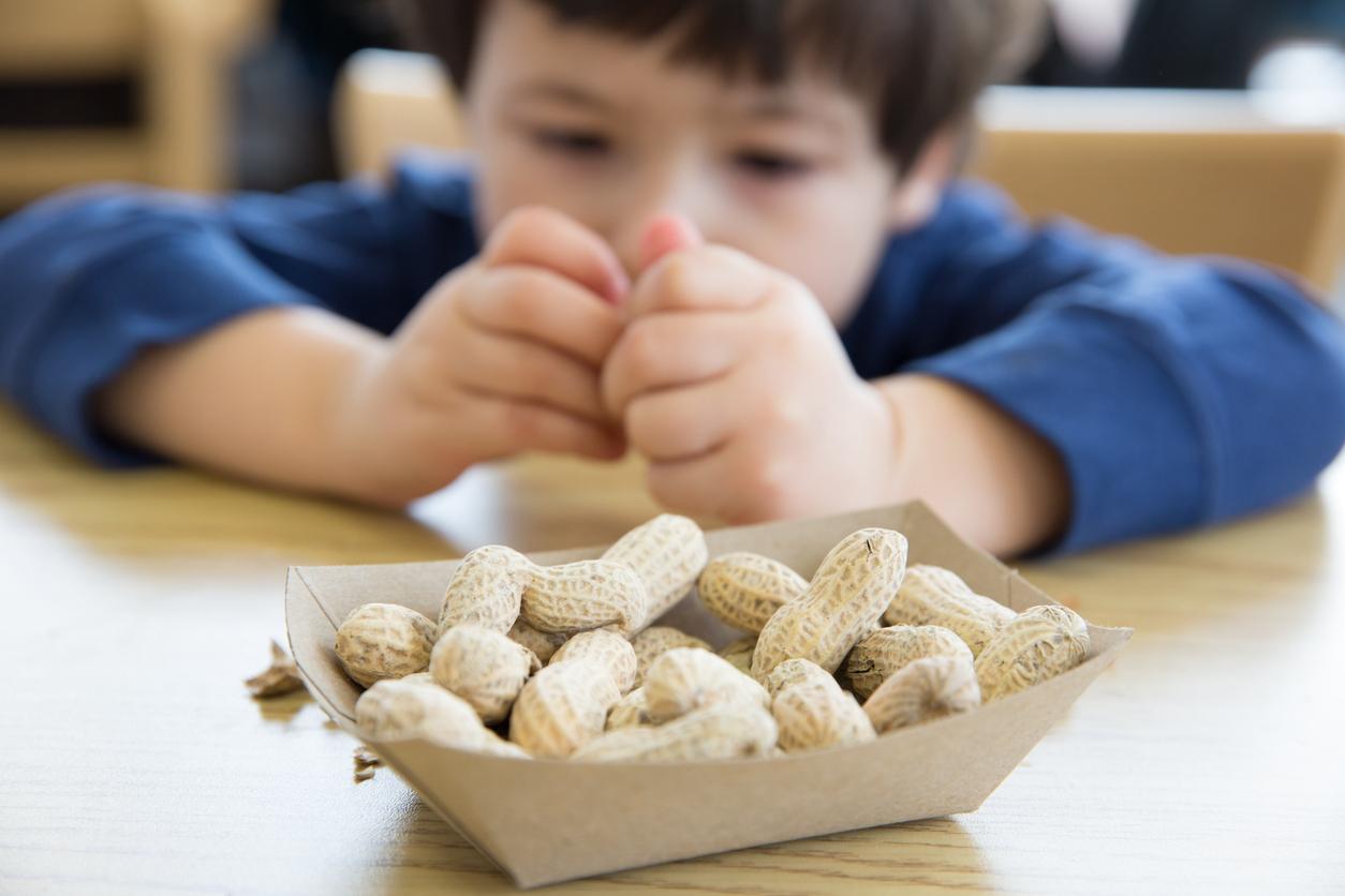 Little boy opening up peanuts to eat in a restaurant