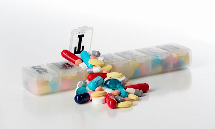Tabletten Wochenorganisier-Box überfüllt mit Tabletten, vor weissem Hintergrund