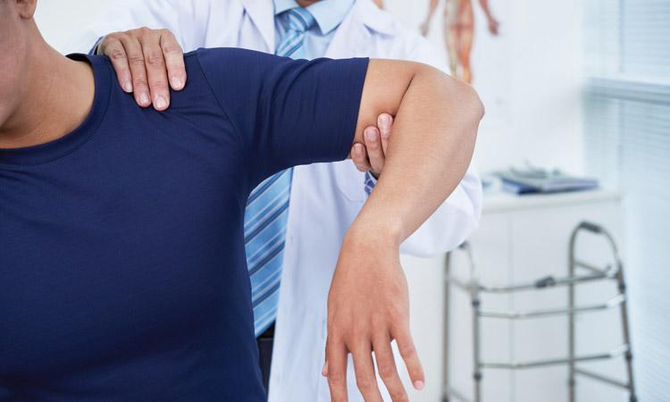 Arzt untersucht Schulter eines männlichen Patienten