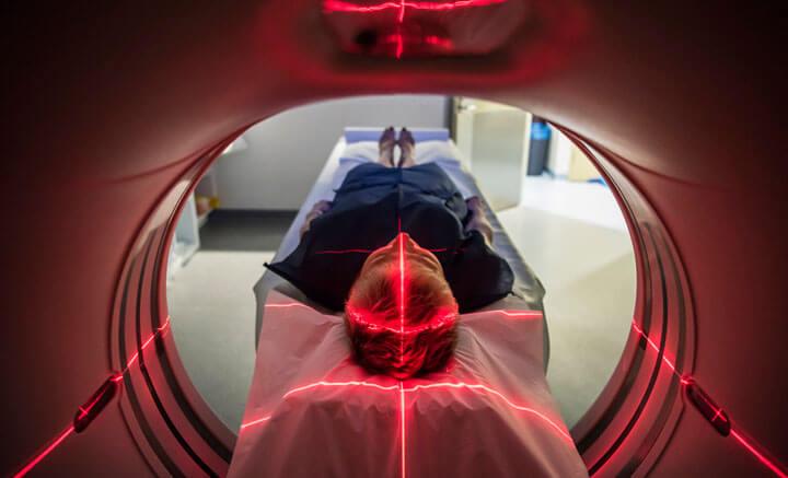 Eine Frau liegt in einem CT Scanner und wird mit roten Markern gescannt