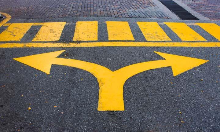 Yellow turn left and turn right arrow sign on asphalt road