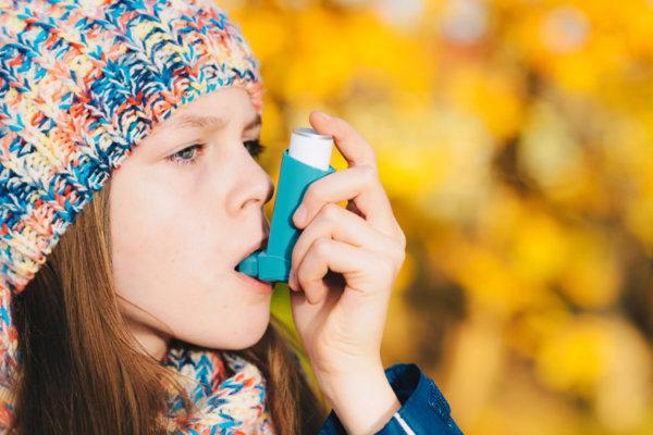 Mädchen im Freien inhaliert mit einem Asthmainhalator.