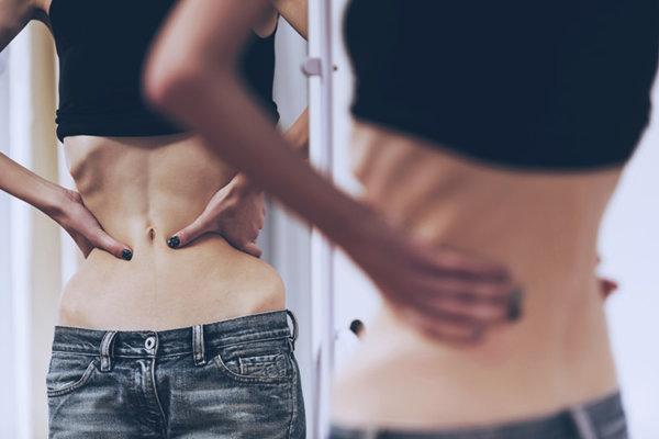 Frau mit Anorexie betrachtet sich im Spiegel
