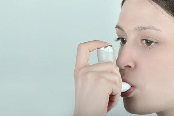 Das Gesicht einer jungen Frau, die gerade einen Asthma Inhalator benutzt.